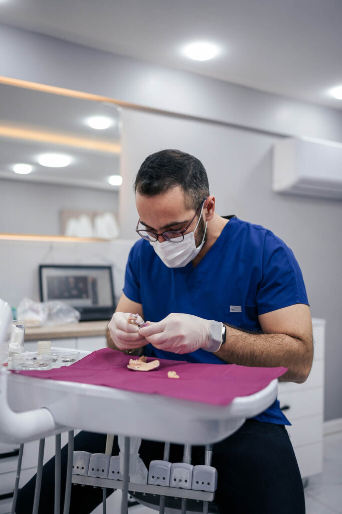Dentist in a clinical setting, examining a patient’s teeth with dental instruments.